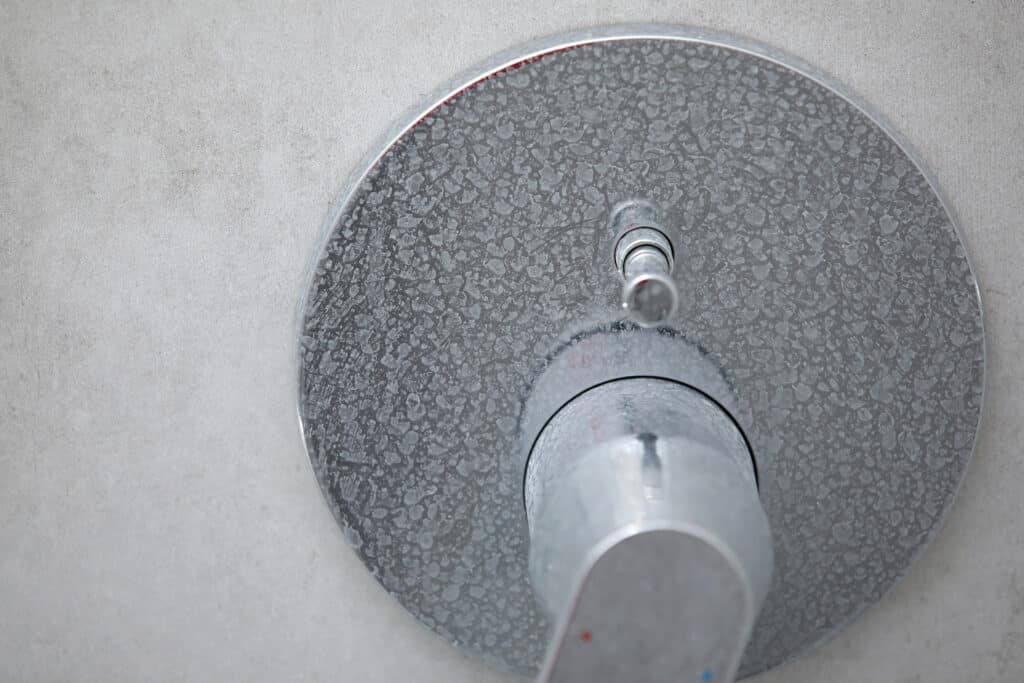 Dirty calcified shower mixer tap, faucet with limescale on it, plaque from water, chrome-plated shower handle.